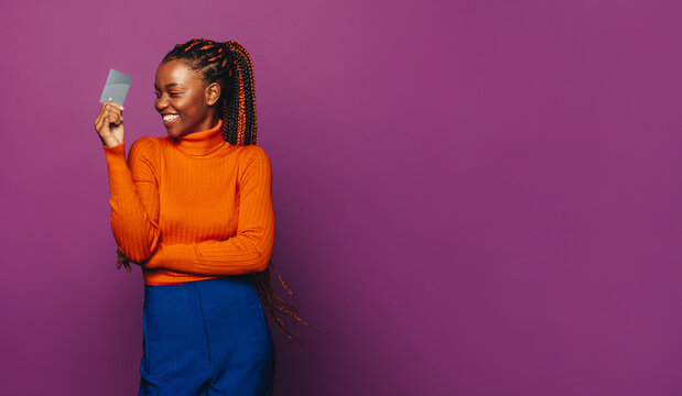 Excited woman paying with contactless card on a vibrant purple background