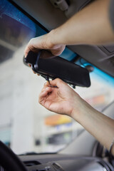 Obraz premium Young woman adjusting smart rear view mirror in car, closeup