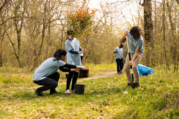 Team of activists planting trees around the woods area for nature preservation, doing voluntary...