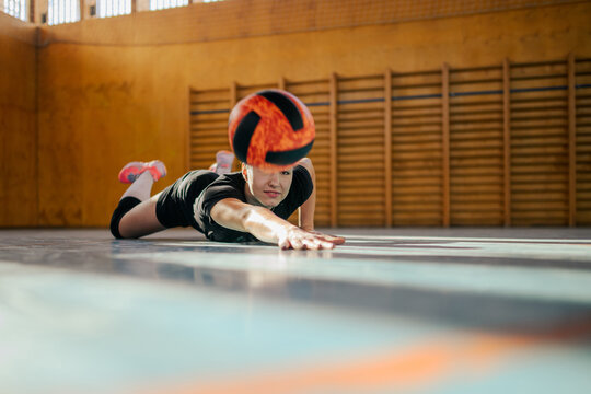 Woman libero of a volleyball female team sliding on a floor in an indoor court