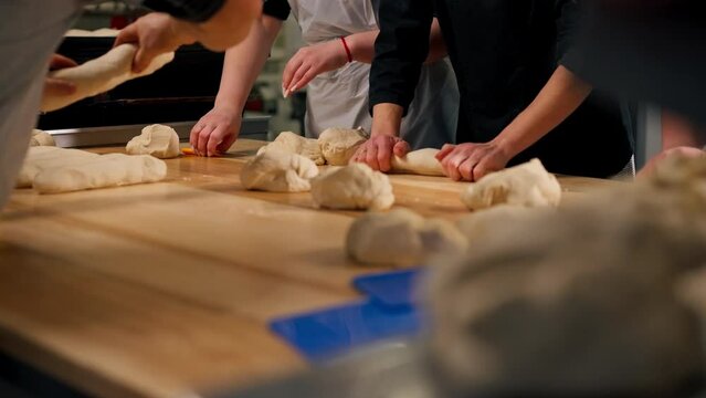 layout in a professional kitchen a group of bakers at the table process the dough and form it into mold