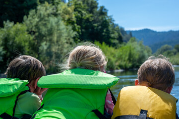 Selective focus on three children peering over a raft going down the wild and scenic Rogue River 