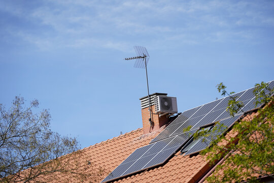 Placas solares sobre tejado de una vivienda y cielo azul. Energ&iacute;a
