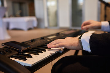A pianist in a suit plays the keyboard with skilled hands