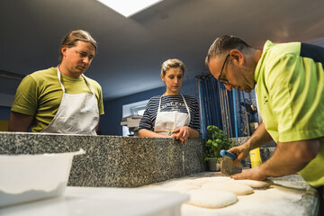 man cook preparing dough in front of his students in the restaurant kitchen. High quality photo