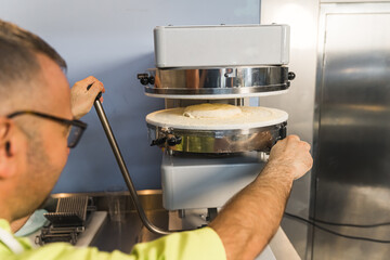 chef pressing dough making machine in the kitchen, pizza and bakery concept. High quality photo