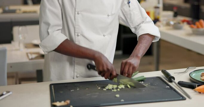 Person, hands and chef or chopping vegetables or cooking in industrial kitchen or cuisine, meal prep or professional. Knife, board and hospitality or customer service in restaurant, prepare or dinner