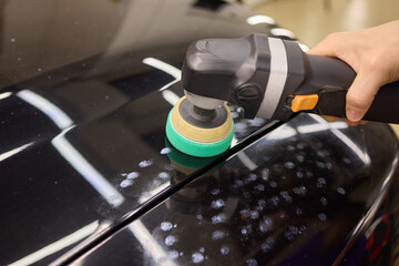 Person using machine to polish black cars automotive exterior