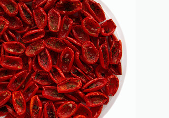 Tomatoes, dried in small pieces, lie in a plate on a white background.