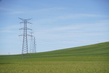  Cables de alta tensión que transportan electricidad  por campos en primavera