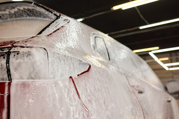 Closeup of red car foamed by liquid, resembling vibrant carmine artwork