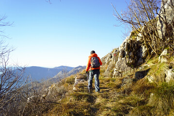 A man walking up a mountain along a marked road. A tourist photographed from behind while hiking in Montenegro.
