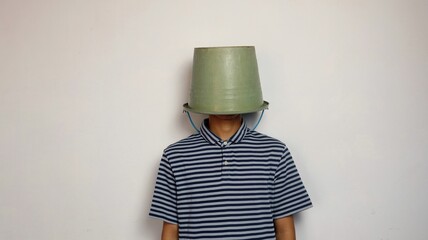 young man using a bucket on his head on a white background