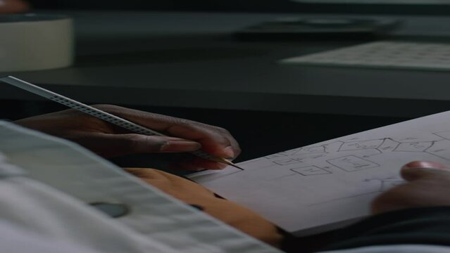 Close-up vertical of hands of unrecognizable African American IT developer drawing algorithm or scheme for software structure in notebook