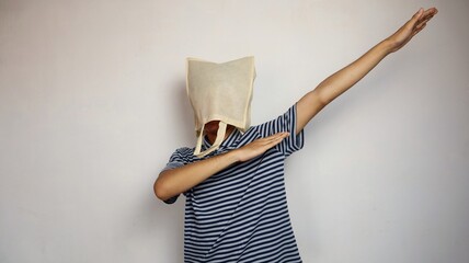 Young Asian man wearing a shopping bag on his head with active hand gestures in a happy-like style