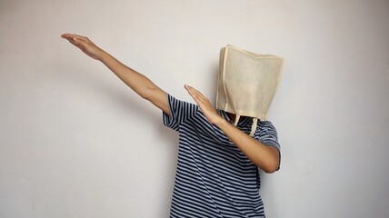 Young Asian man wearing a shopping bag on his head with active hand gestures in a happy-like style