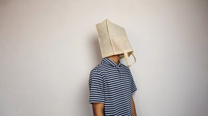 young Asian man wearing a shopping bag on his head - obrazy, fototapety, plakaty
