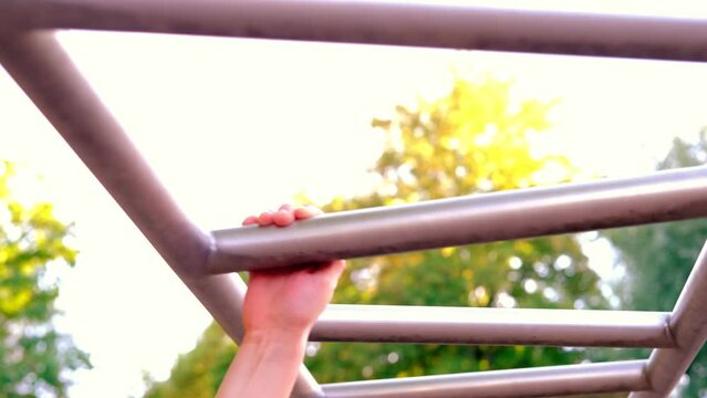 child, boy 8-9 years with blue hair climbing pipes of metal sports projectile, natural green background, concept of cheerful childhood, self-identification, sports achievements, physical development