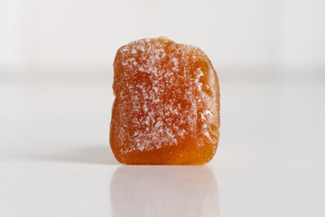 a chewy ginger candy sprrinkled with powdered sugar on white background, close up macro with copy space