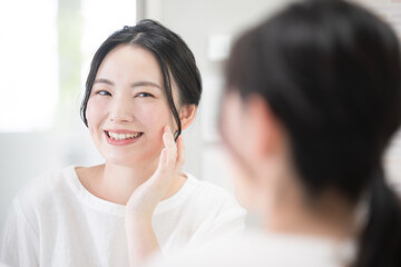 Woman concerned about skin texture while looking in the mirror Image of skin care and beauty