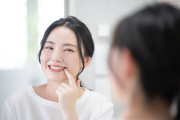 Cute woman looking at her teeth and whiteness while looking in the mirror Whitening, etc. Close-up