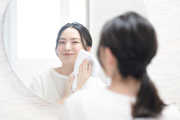 Woman holding towel and washing face in washbasin mirror Close-up