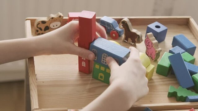 smart child, schoolboy playing with educational toy, wooden geometric figures, blocks in boy's hands, developing brain games, concept childhood, earlier child development, creativity, early training
