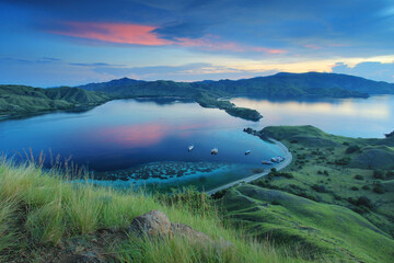 view of the sea surrounded by hills with green grass with the dark green color of the sea and the...