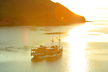 views of the sea and hills with a yellowish sky and sea with dazzling sunlight and a ship sailing on Gili Lawa land © Abdurrahman