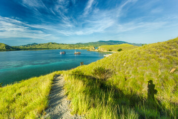 view of the sea surrounded by hills and the sea which seems greenish with the hills covered with green grass and there are two ships sailing in the middle on Gili Lawa land © Abdurrahman