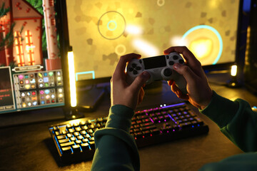 Man playing video games with controller at table indoors, closeup