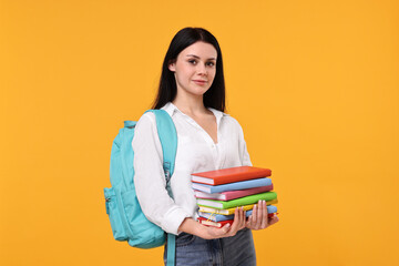Student with stack of books on yellow background