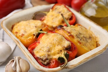 Delicious stuffed peppers in baking dish on white table, closeup