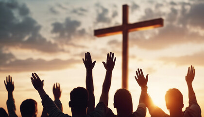 Christian worshipers raising hands up in the air in front of the cross, sunset

