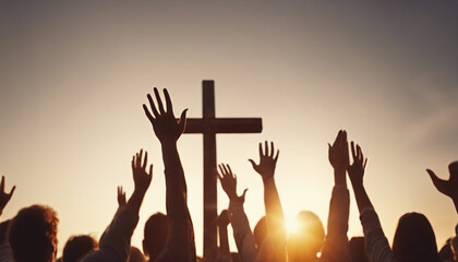 Christian worshipers raising hands up in the air in front of the cross, sunset  