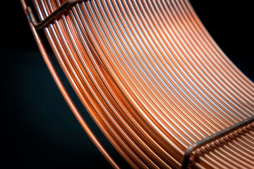Elegantly curved copper wires on dark background, industrial beauty. Coil of thick copper wire,...