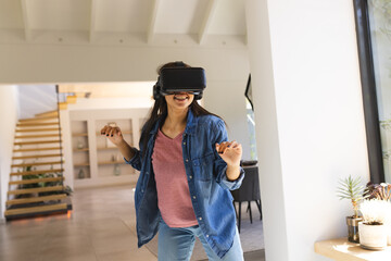 A young biracial female, wearing VR headset, enjoying virtual reality at home