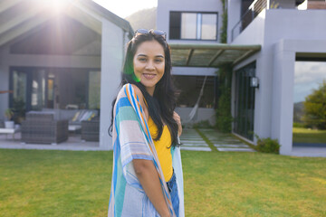 Biracial young woman standing outdoors in front of house