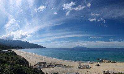 Yakushima coast panorama on sunny day, Inakahama sandy beach turquoise sea water, blue sky, distant Kuchierabujima isalnd