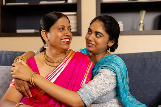 Indian mother and teenage daughter, sharing laughter in cozy room