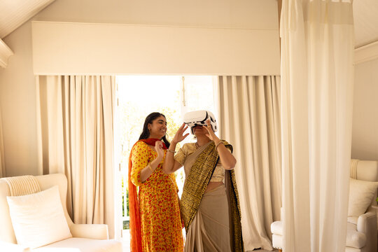 Indian mother and teenage daughter trying out virtual reality headset at home - Powered by Adobe