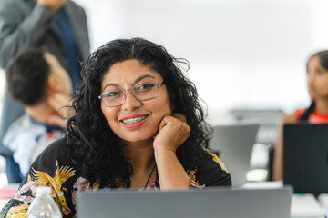 Close-up portrait of a smiling Latina woman looking at the camera at the university. 