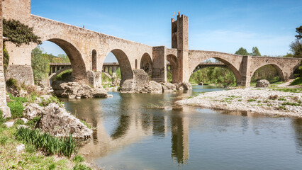 The medieval bridge of Besalú, Girona, is reflected on a river.
