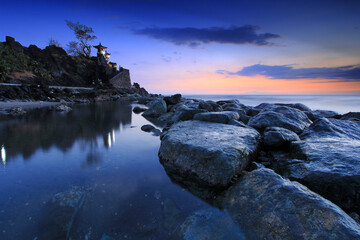 clean sea water and lots of rocks lined up near the sea with sunset nuances with slightly purplish...
