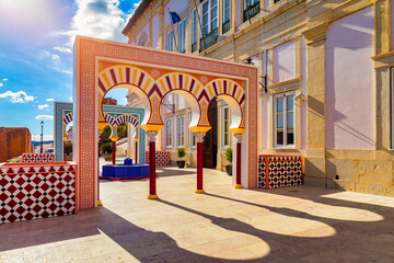 View of Silves town buildings with a red and white archway and a blue fountain, Algarve region,...