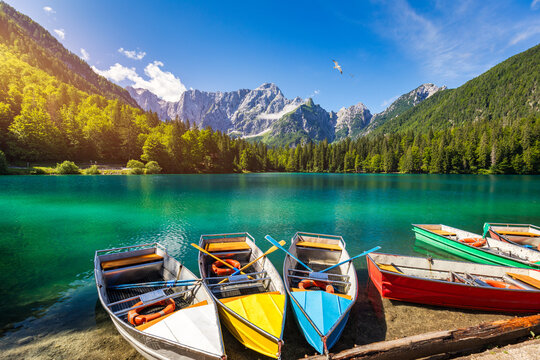 Picturesque lake Lago Fusine with colorful boats. Fusine lake with Mangart peak on background. Popular travel destination of Julian Alps. Location: Tarvisio comune , Province of Udine, Italy, Europe.