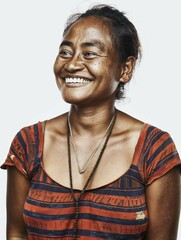 Portrait of a smiling Fijian woman with jewellery on a white backdrop.