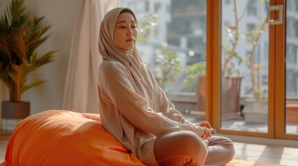 woman instructor wearing hijab doing yoga pilates pose tutorial on orange mattress in a room