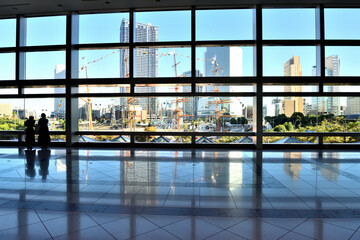 横浜超高層ビルのロビーから外を眺める人々のシルエット