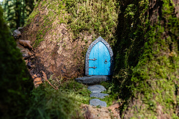 small blue door made of polymer clay on in nature like a fairy house close up